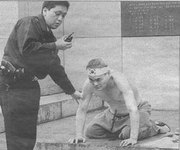 Un policía ayuda a Yang Bong-ho tras hacerse el haraquiri.