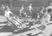 Unos padres corren la 27ª edición del maratón Popular de Madrid llevando a sus hijos en los carritos.