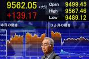 Un hombre pasa delante de una pantalla que muestra el valor alcanzado por el índice Nikkei de la Bolsa de Tokio.